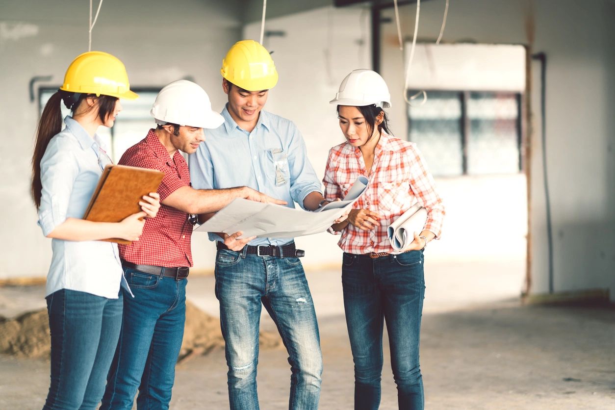 A group of people standing around looking at plans.